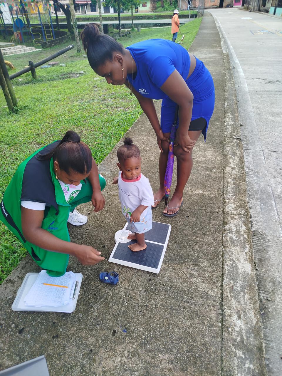 Profesional de Manos Amigas realizando control de peso a bebé como parte del programa de seguimiento nutricional comunitario